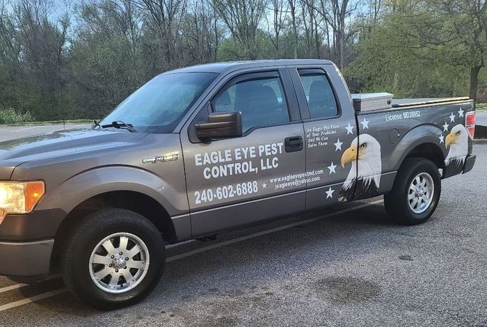An eagle eye pest control truck is parked in a parking lot.