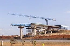 A bridge is being built on top of a hill next to a road.