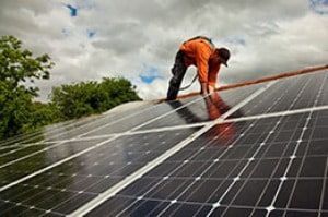 A man is installing solar panels on a roof.