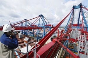 A man wearing a hard hat is standing on the deck of a ship.