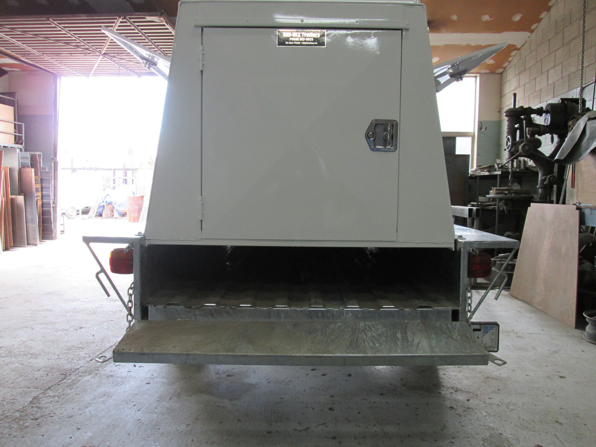 Gray trailer with canvas cover parked in a grassy field.