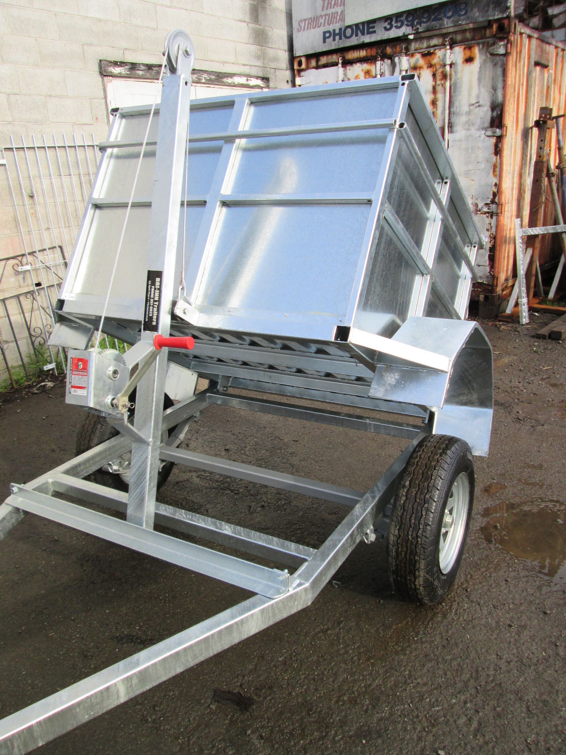 Silver tipping trailer with black tires, angled upwards.