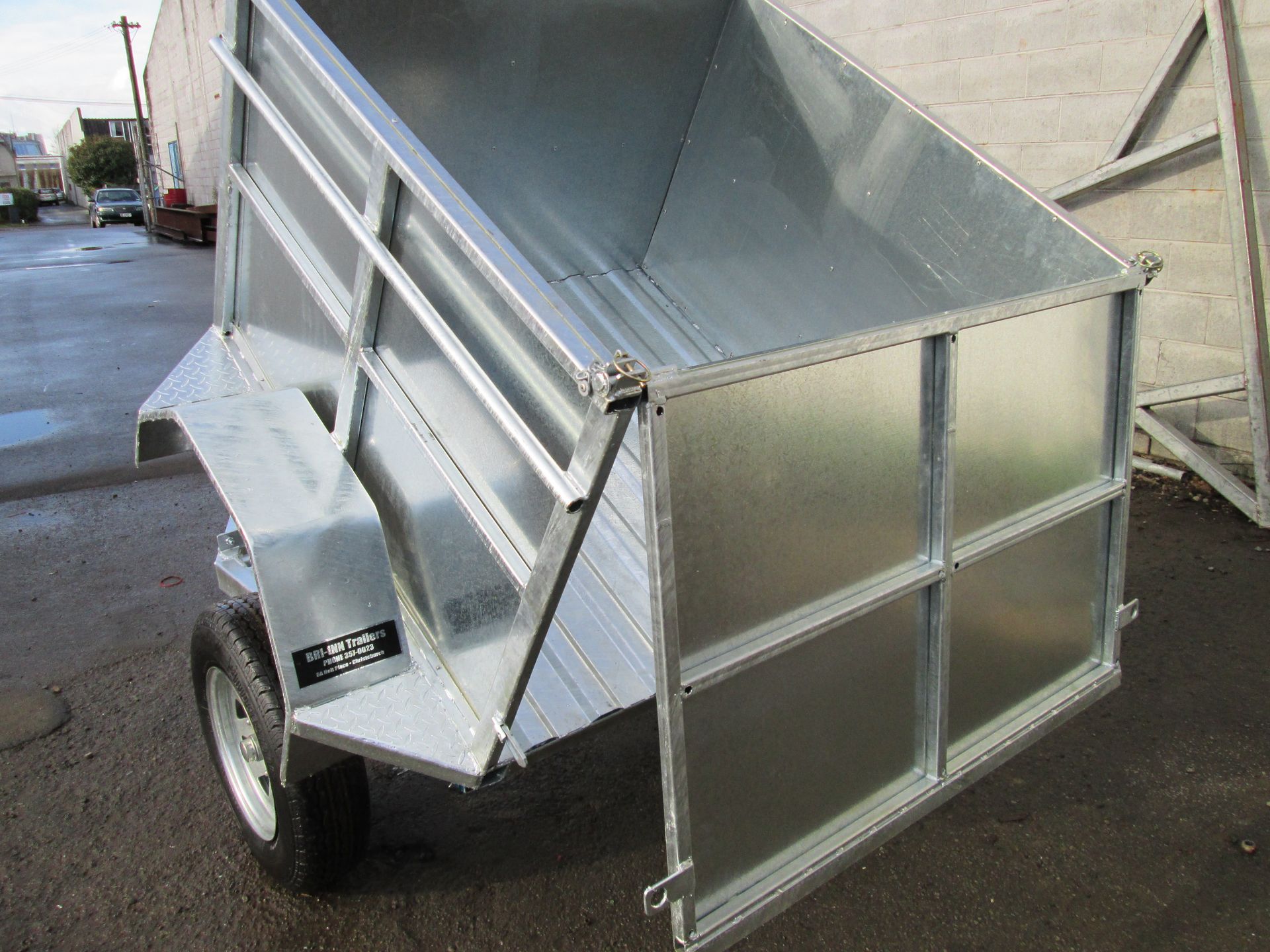 Galvanized metal dump trailer, open, angled upward.