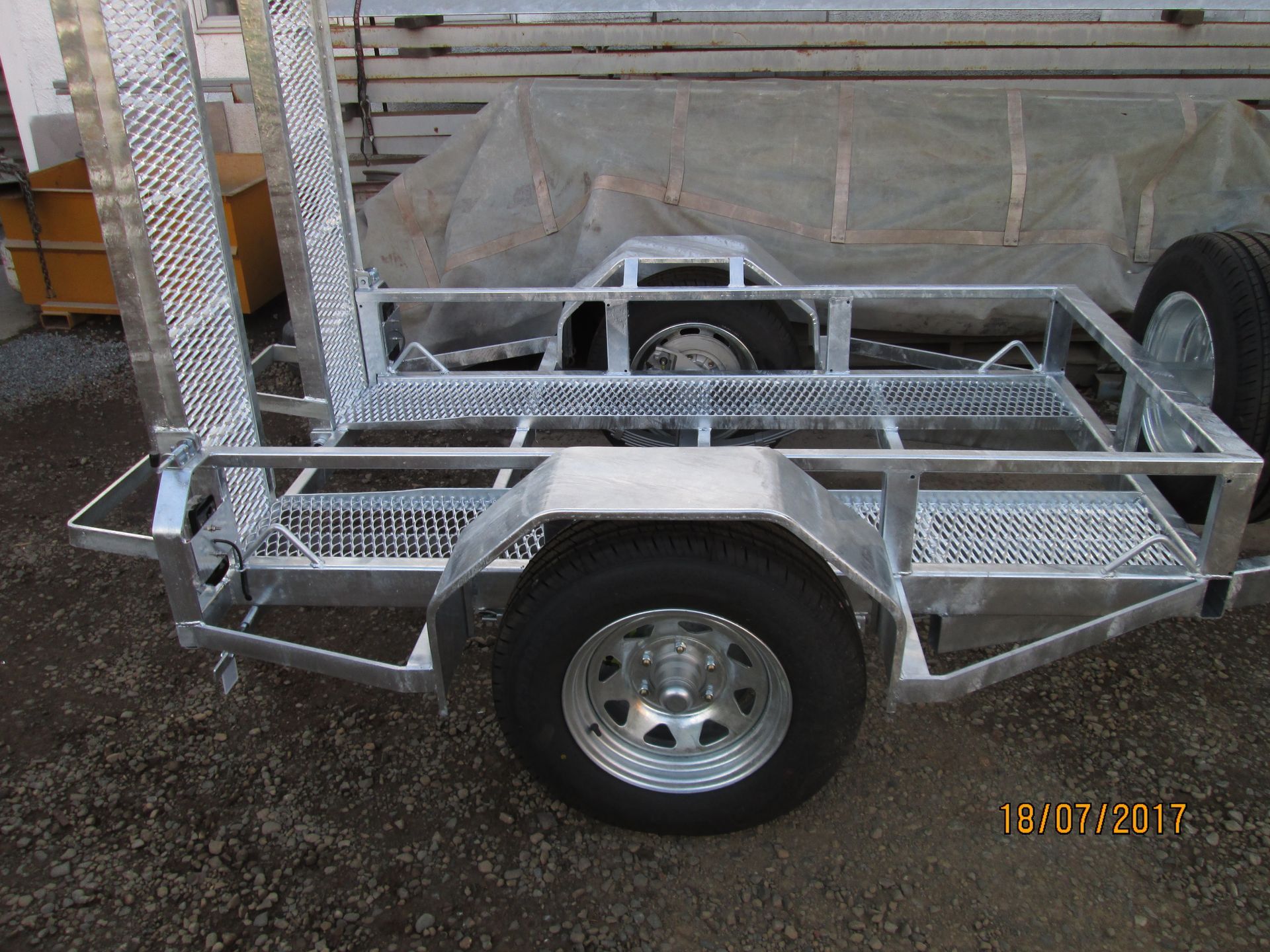 Aluminum trailer with diamond plate floor and sides, black tires, and silver rims.
