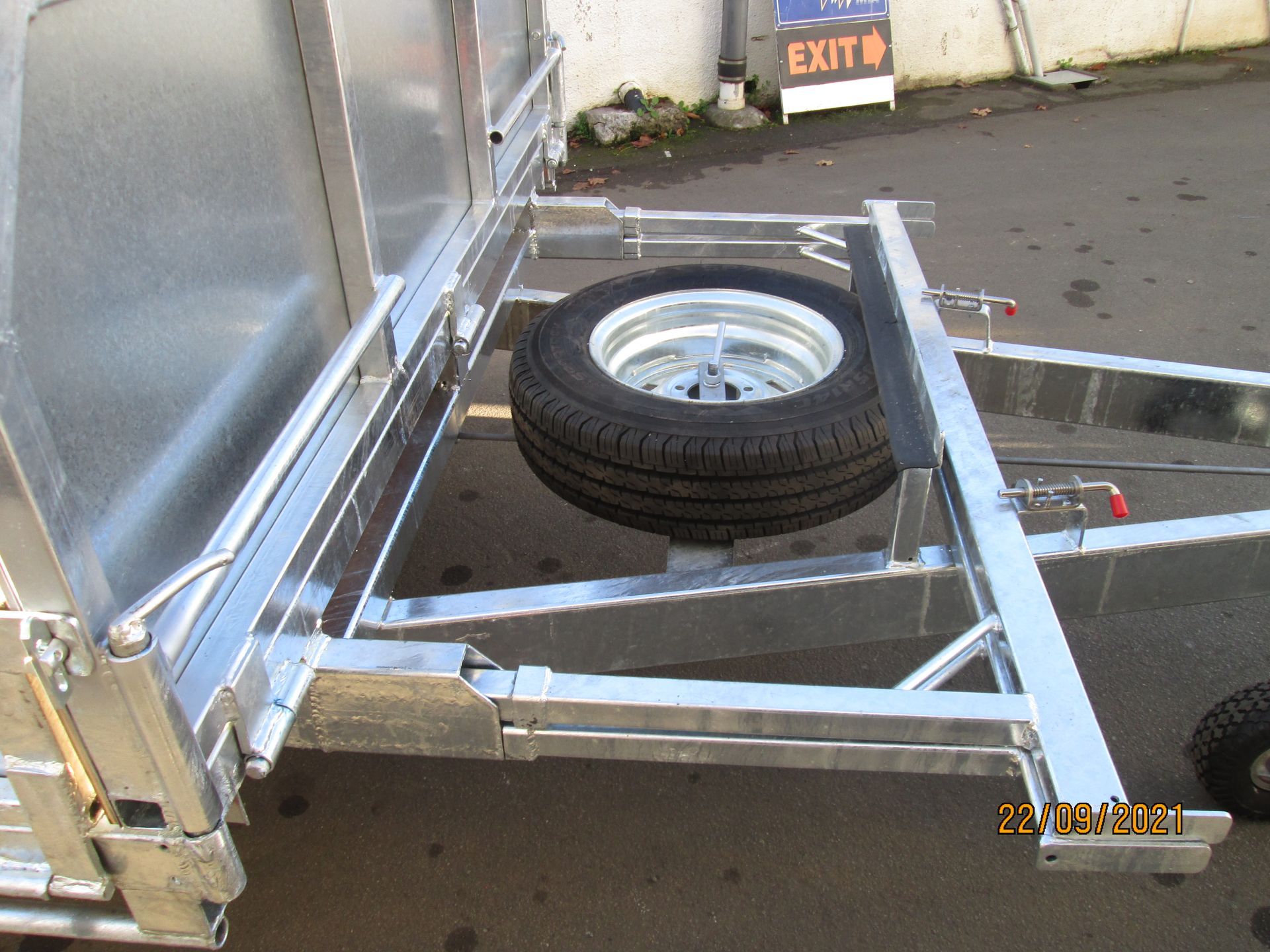 A galvanized metal trailer with a spare tire mounted on the frame.