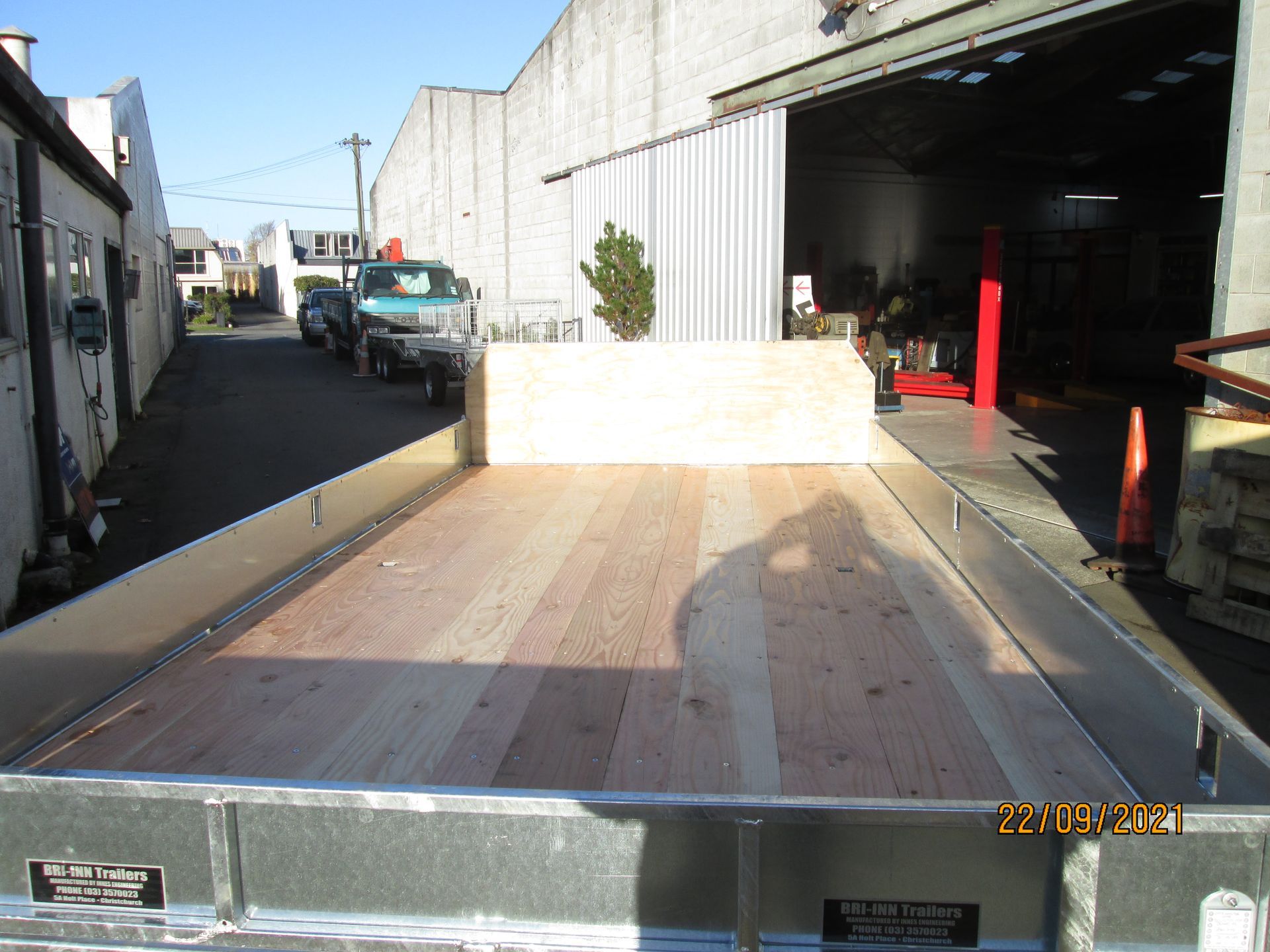 Flatbed truck with wooden floor, parked outside a building.