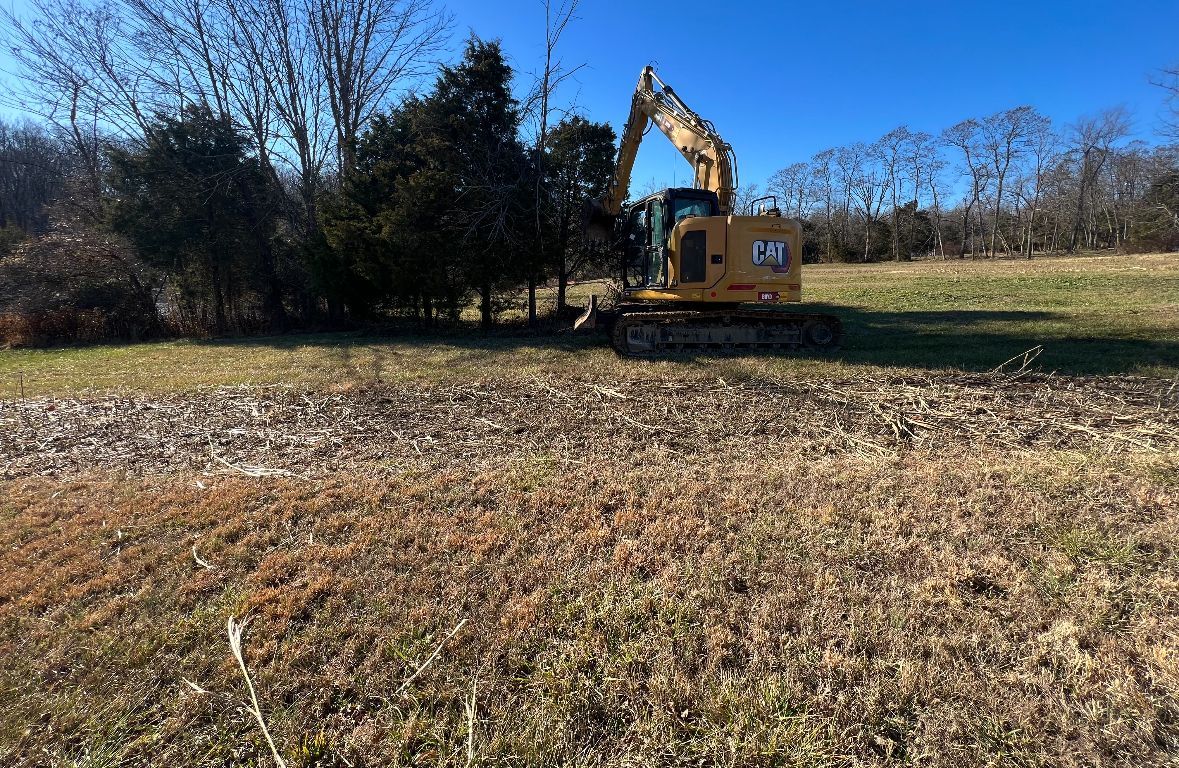 A Yellow Excavator is Working in a Field — Scottsburg, IN — Babbs Land Management LLC