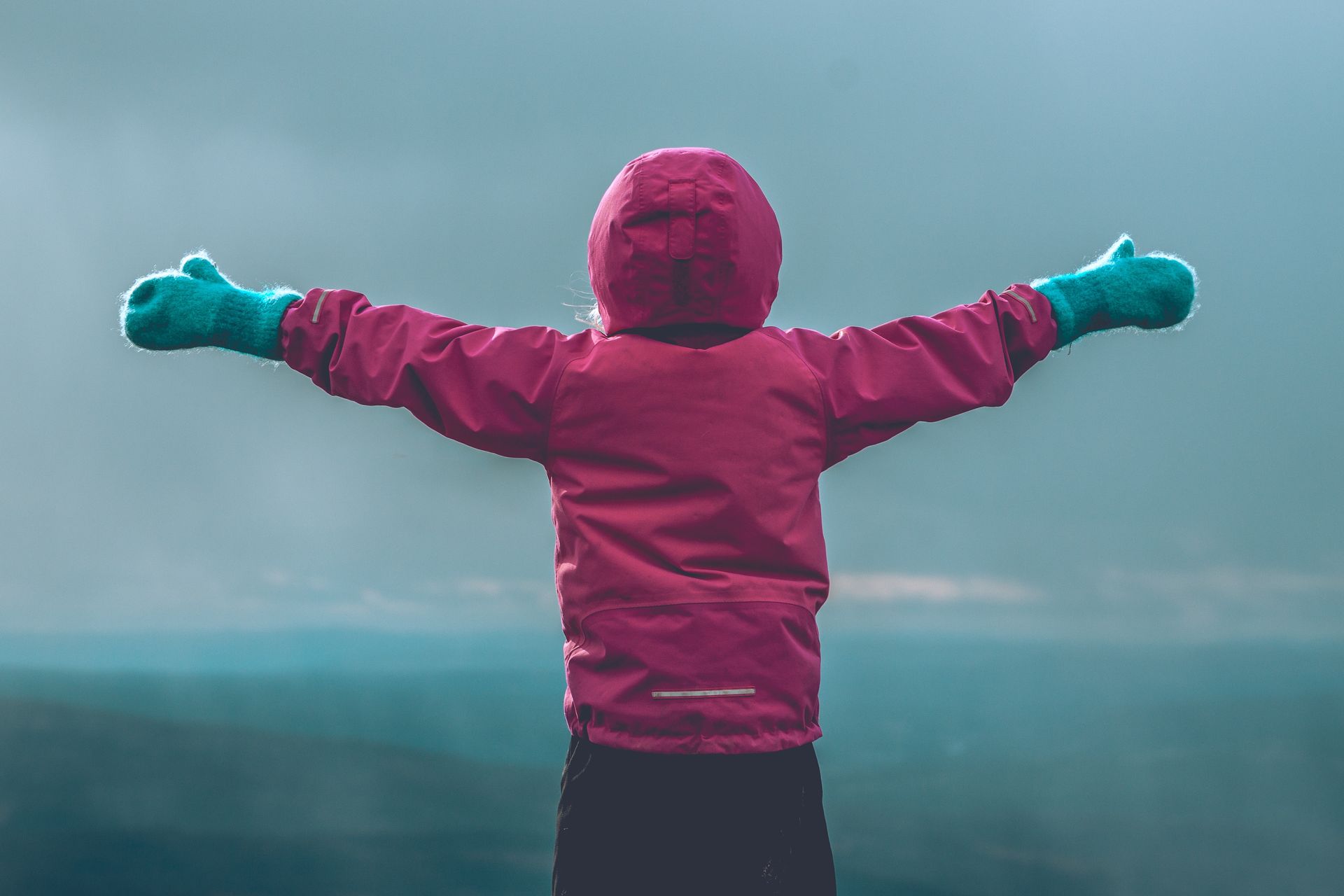 Early years child in winter wear with open arms