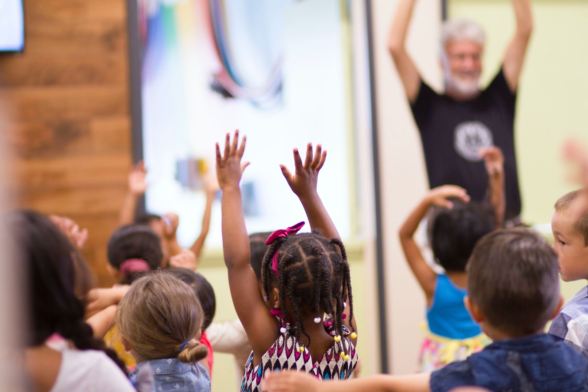 Early Years Classroom with children trusting adult and copying hands up action