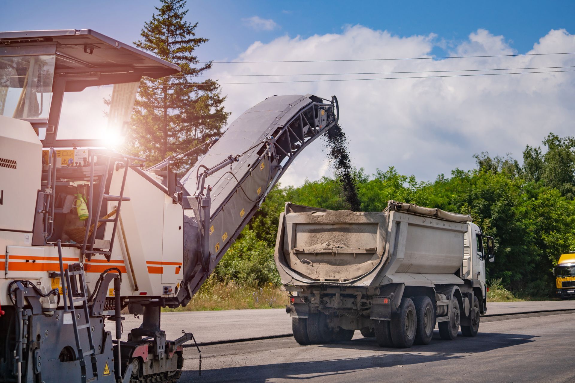 Heavy machine breaks up the asphalt and deposits it in a Dump Truck