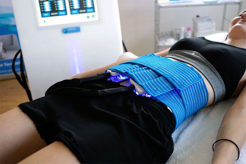 Eine Frau liegt mit einem blauen Gürtel um die Taille auf einem Bett