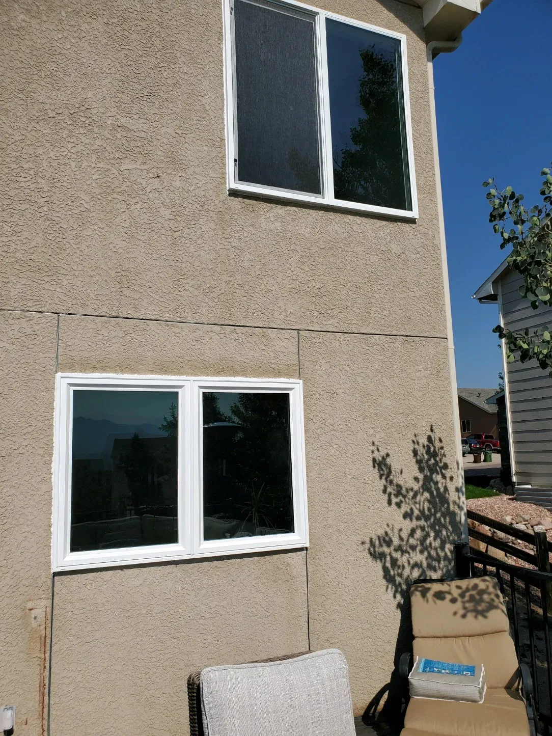 A house with two windows and a chair in front of it