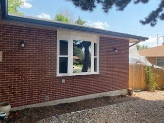A brick house with a large window on the side of it.