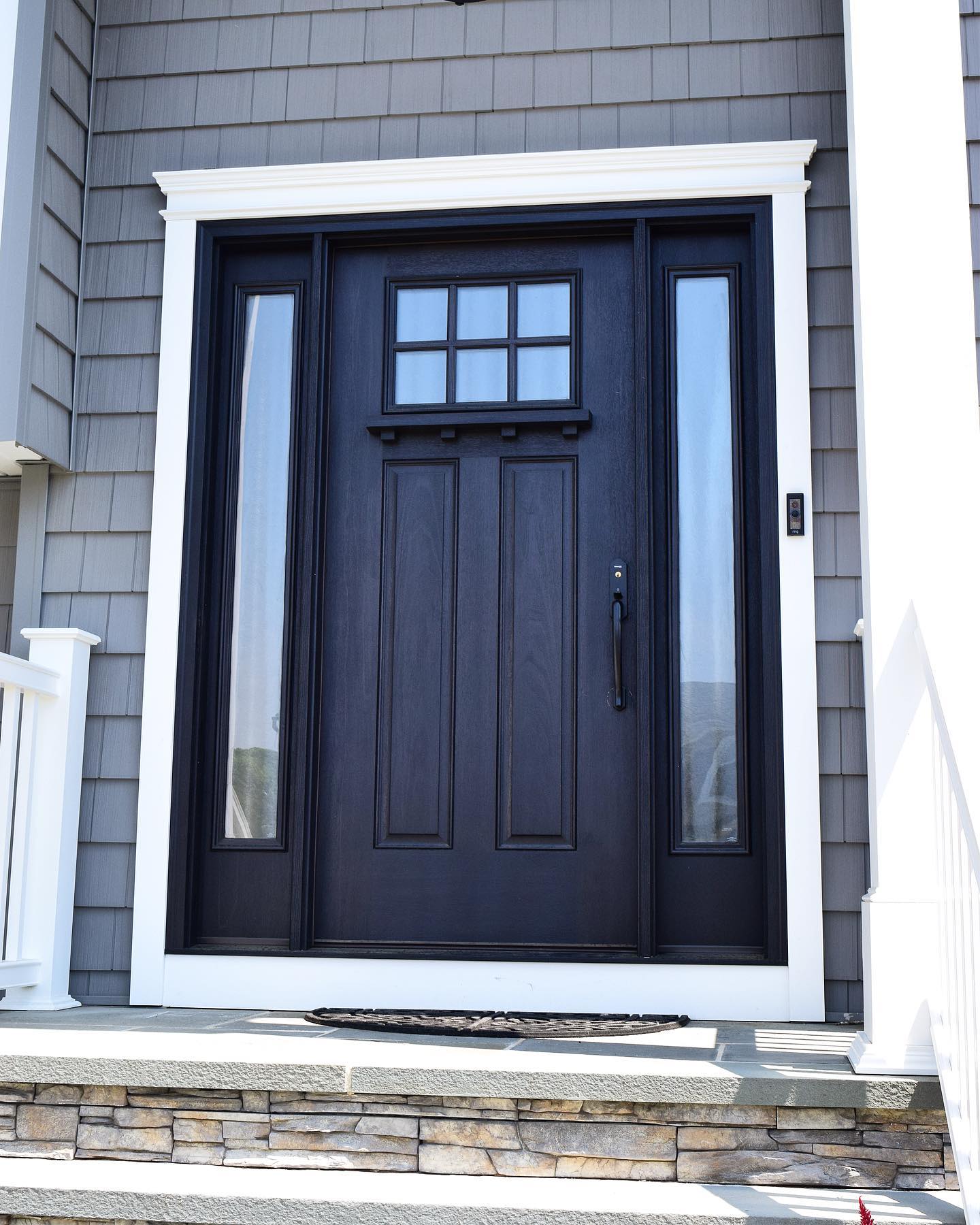 A black door with a white trim is on the front of a house