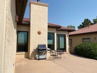 A patio with a grill and a table and chairs in front of a house.