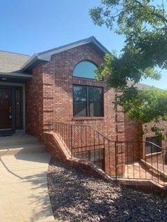 A brick house with a large window and stairs leading up to it.