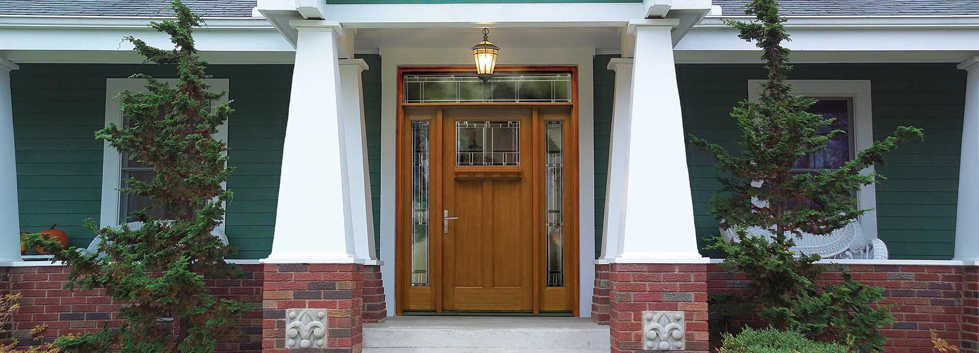 The front door of a green house with a wooden door