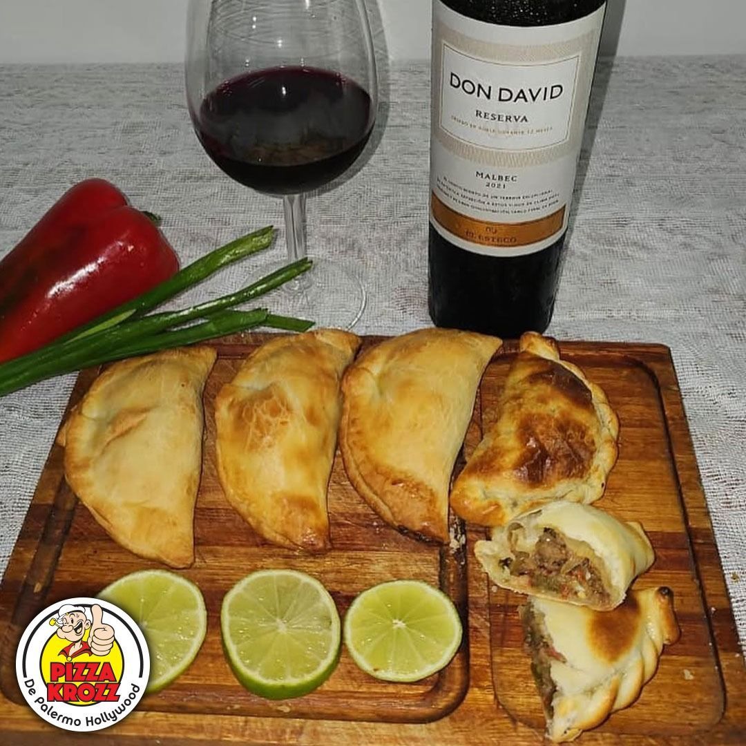 Una tabla de madera sostiene cuatro empanadas horneadas