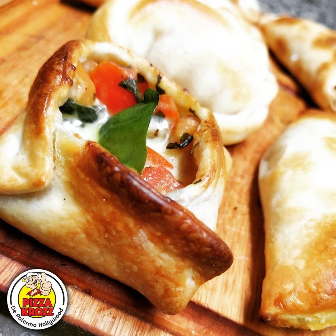 Varias empanadas horneadas rellenas de tomates, verduras y queso