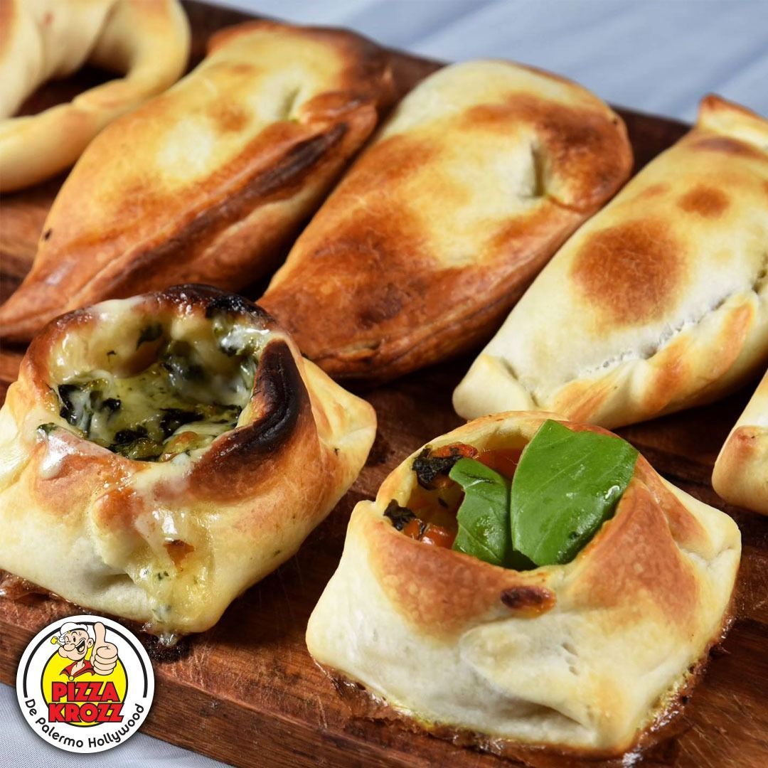 Una tabla de madera que contiene varias empanadas horneadas y pasteles salados abiertos