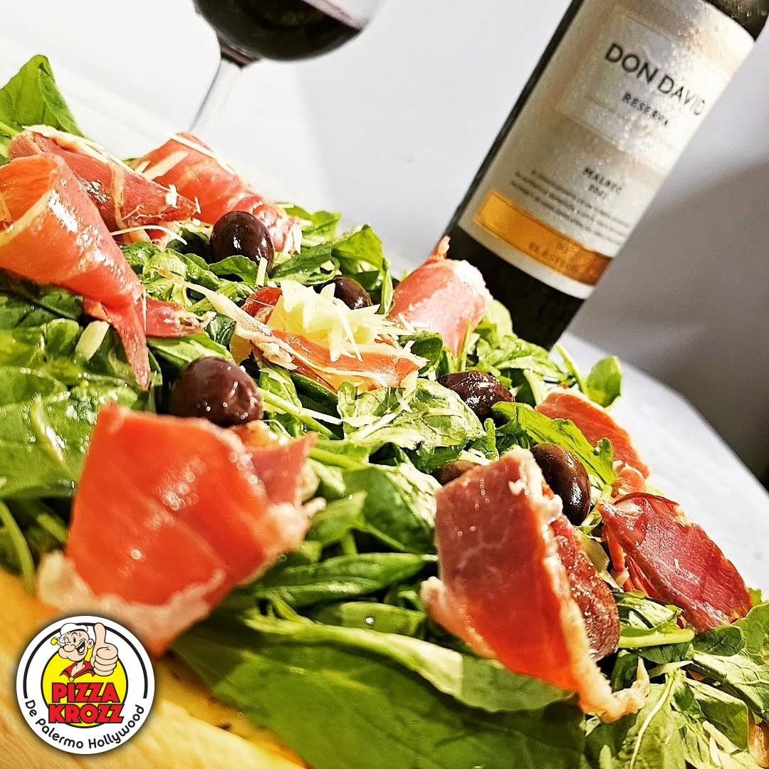 Un primer plano de una ensalada fresca cubierta con rodajas de jamón curado