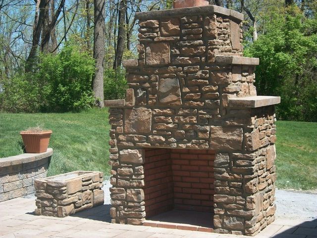 A Stone Fireplace in A Backyard with Trees in The Background