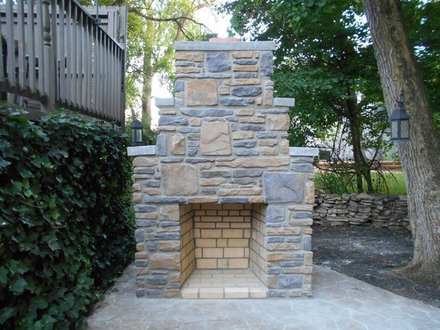 A Stone Fireplace in A Backyard with Trees in The Background