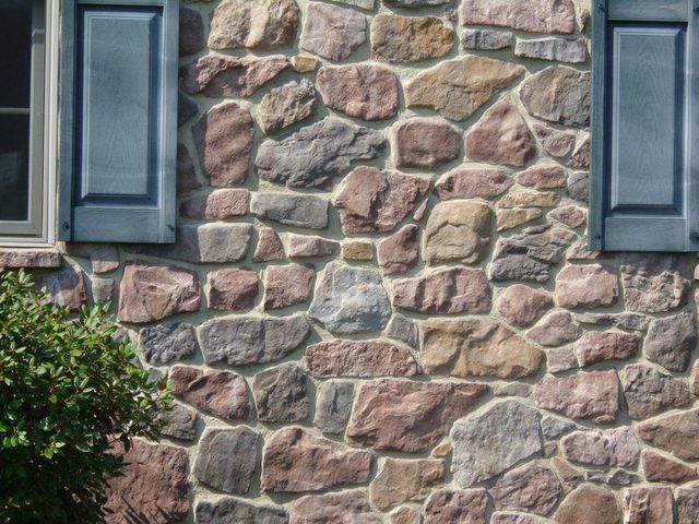 A stone wall with blue shutters and a window