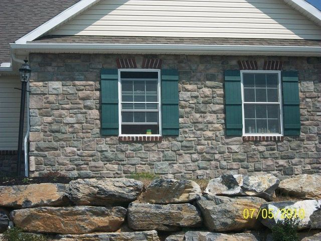 A Stone House with Green Shutters on The Windows