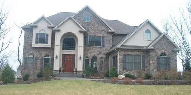 A Large House with A Lot of Windows Is Sitting on Top of A Lush Green Hillside.