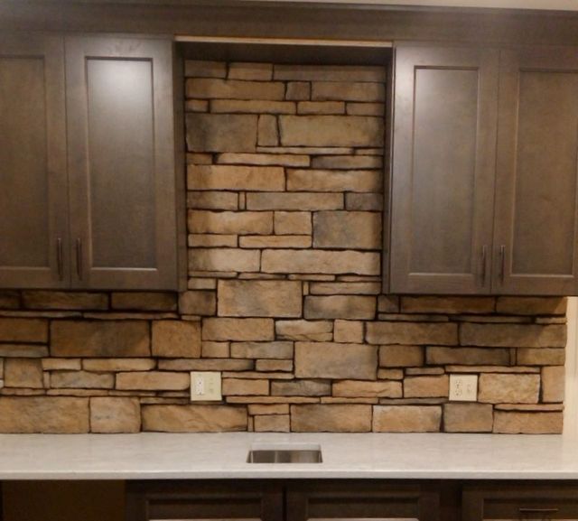 A Kitchen with A Stone Wall and Wooden Cabinets