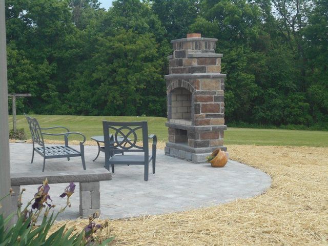 A Brick Fireplace Sits on A Patio with Chairs and A Table