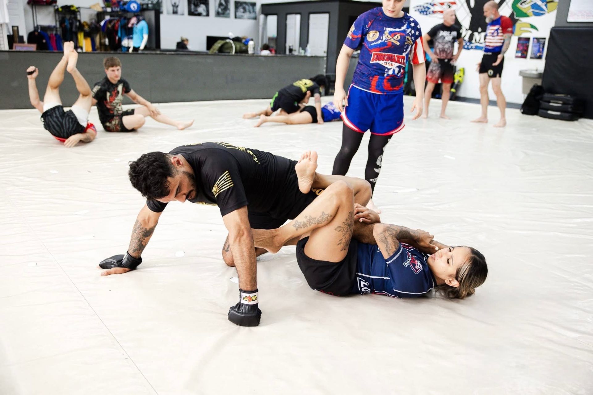 a man and a woman are wrestling on a mat in a gym .