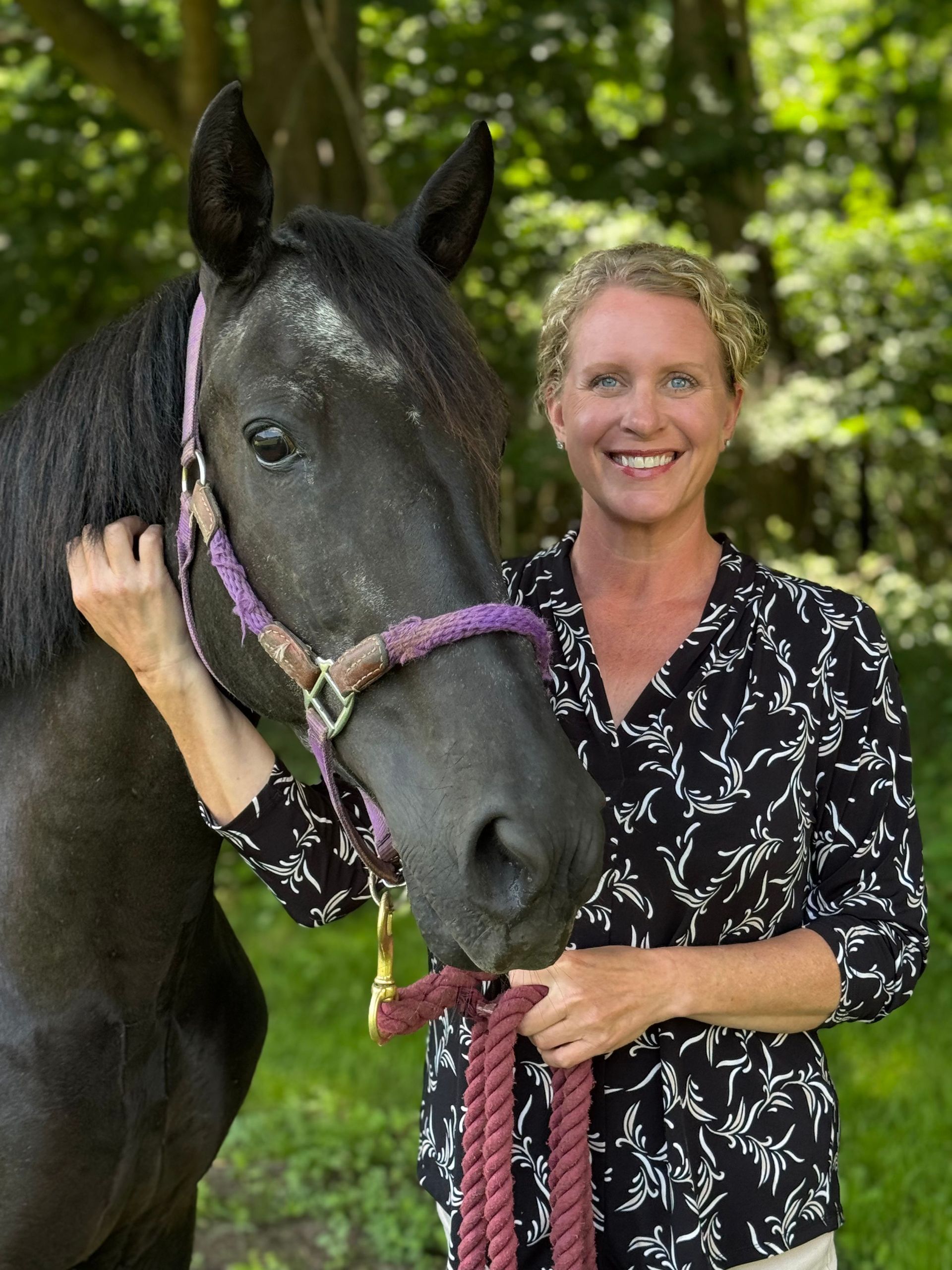 A woman standing next to a brown horse wearing a shirt that says ' saddle ' on it