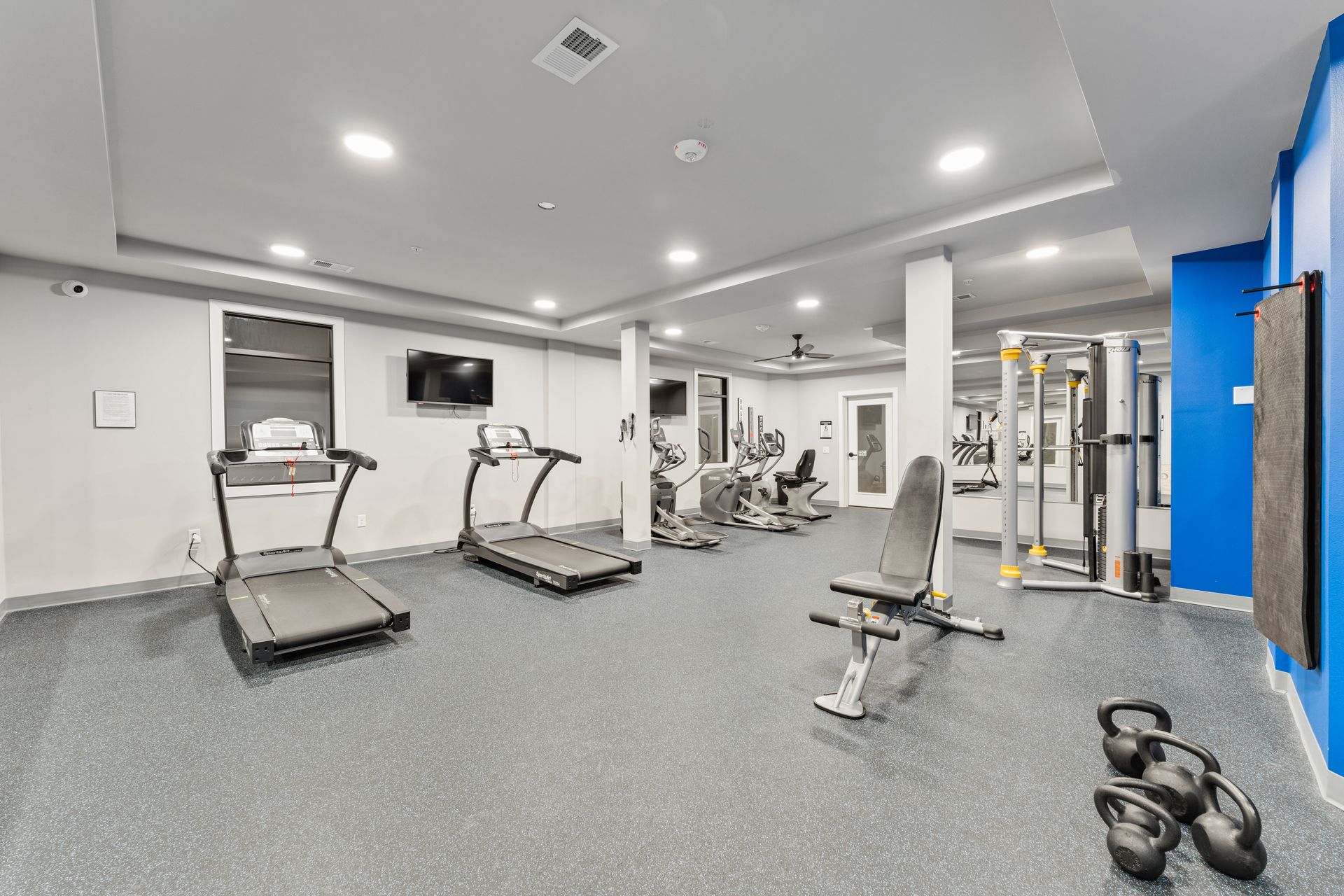 a gym with treadmills and a tv on the wall