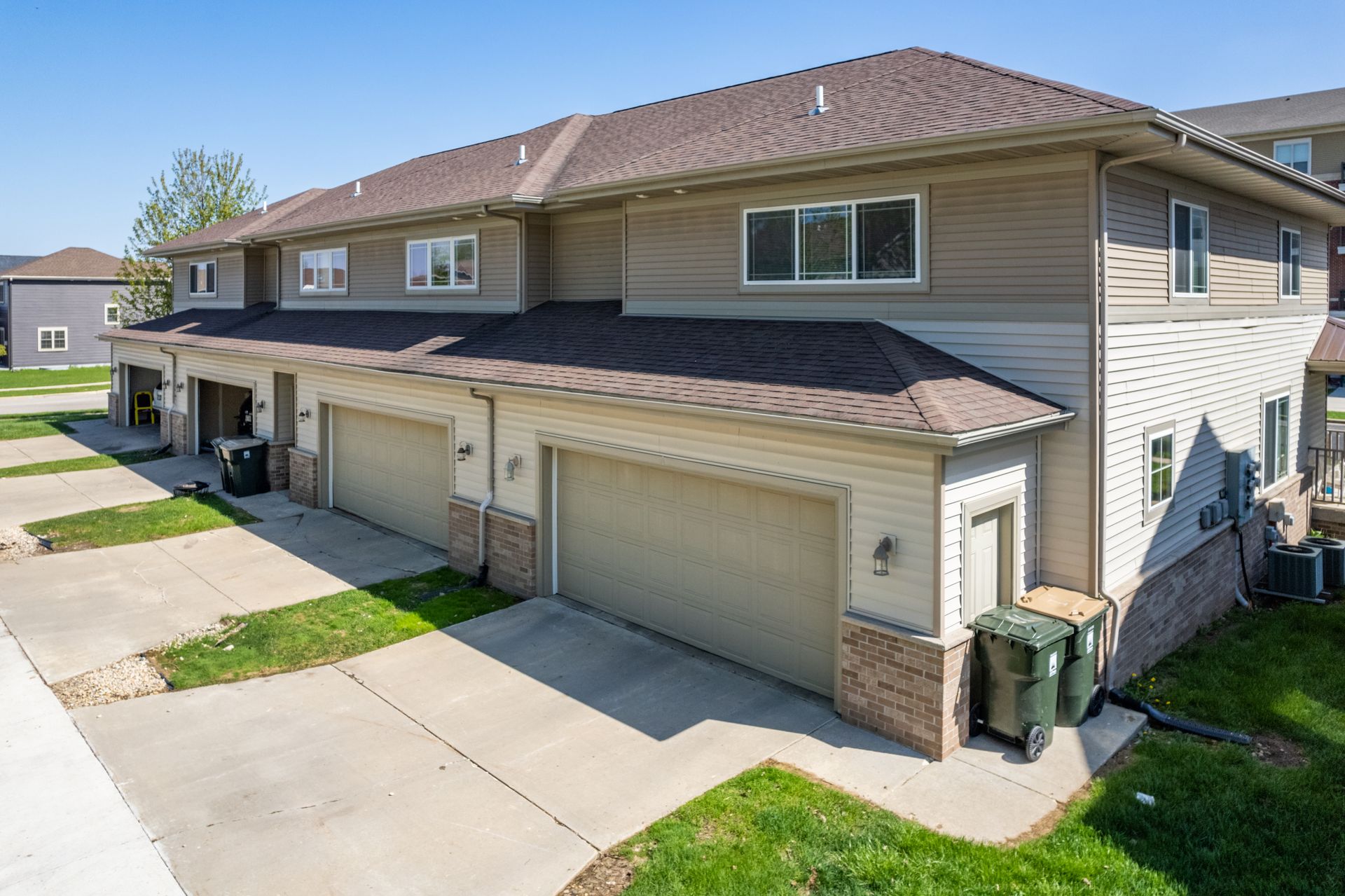 a row of houses with garages and trash cans in front of them