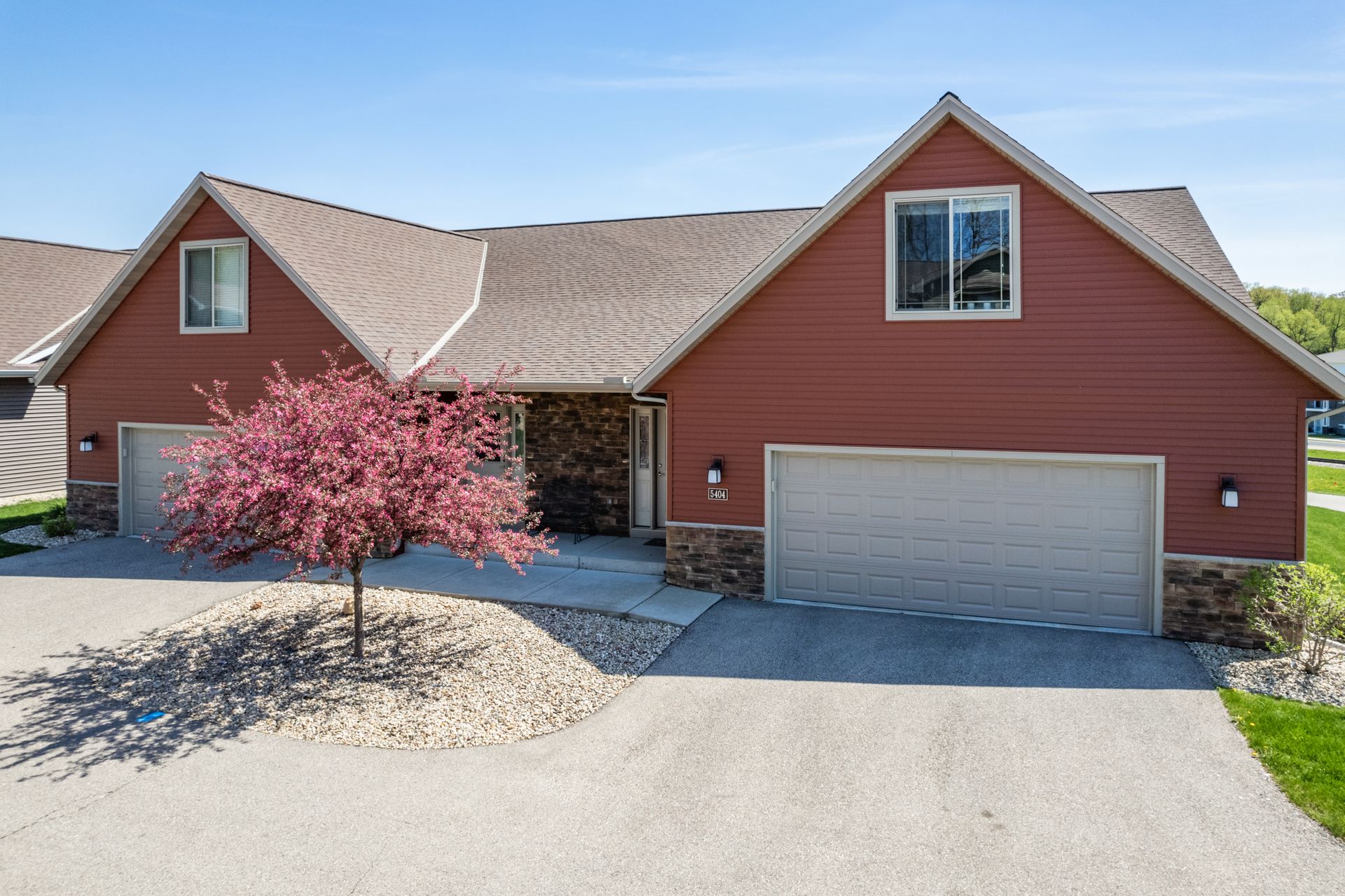 a red house with a white garage door and a tree in front of it