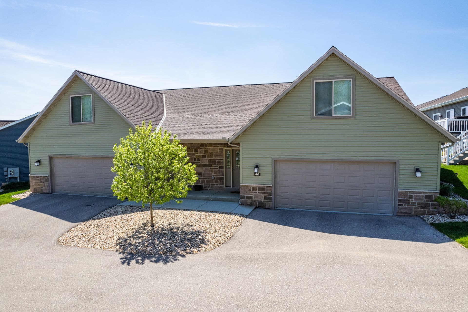 a house with two garage doors and a tree in front of it