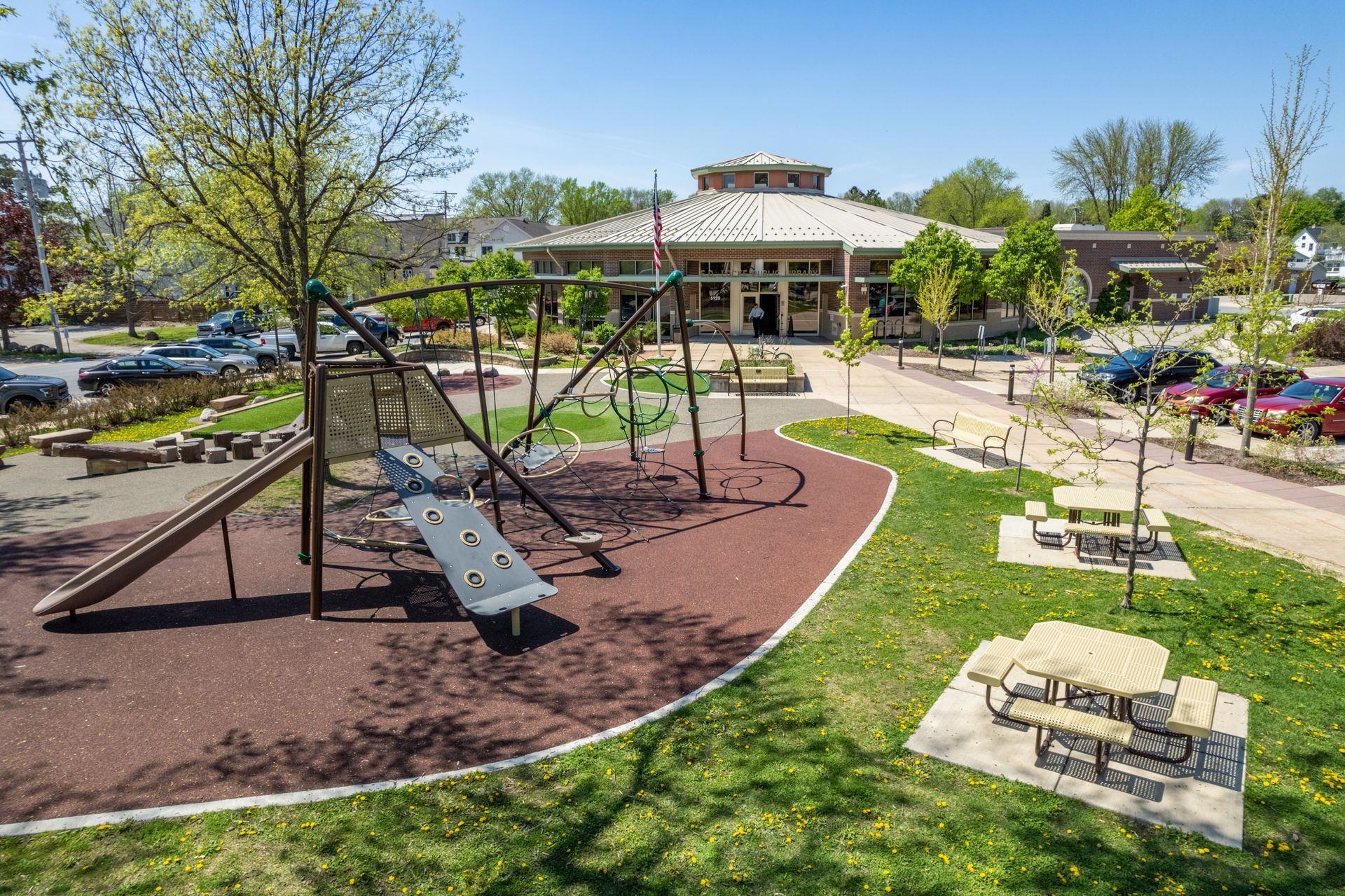 a playground with a slide and swings in front of a building