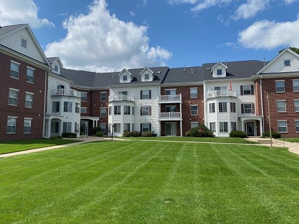 a large apartment building with a lush green lawn in front of it .