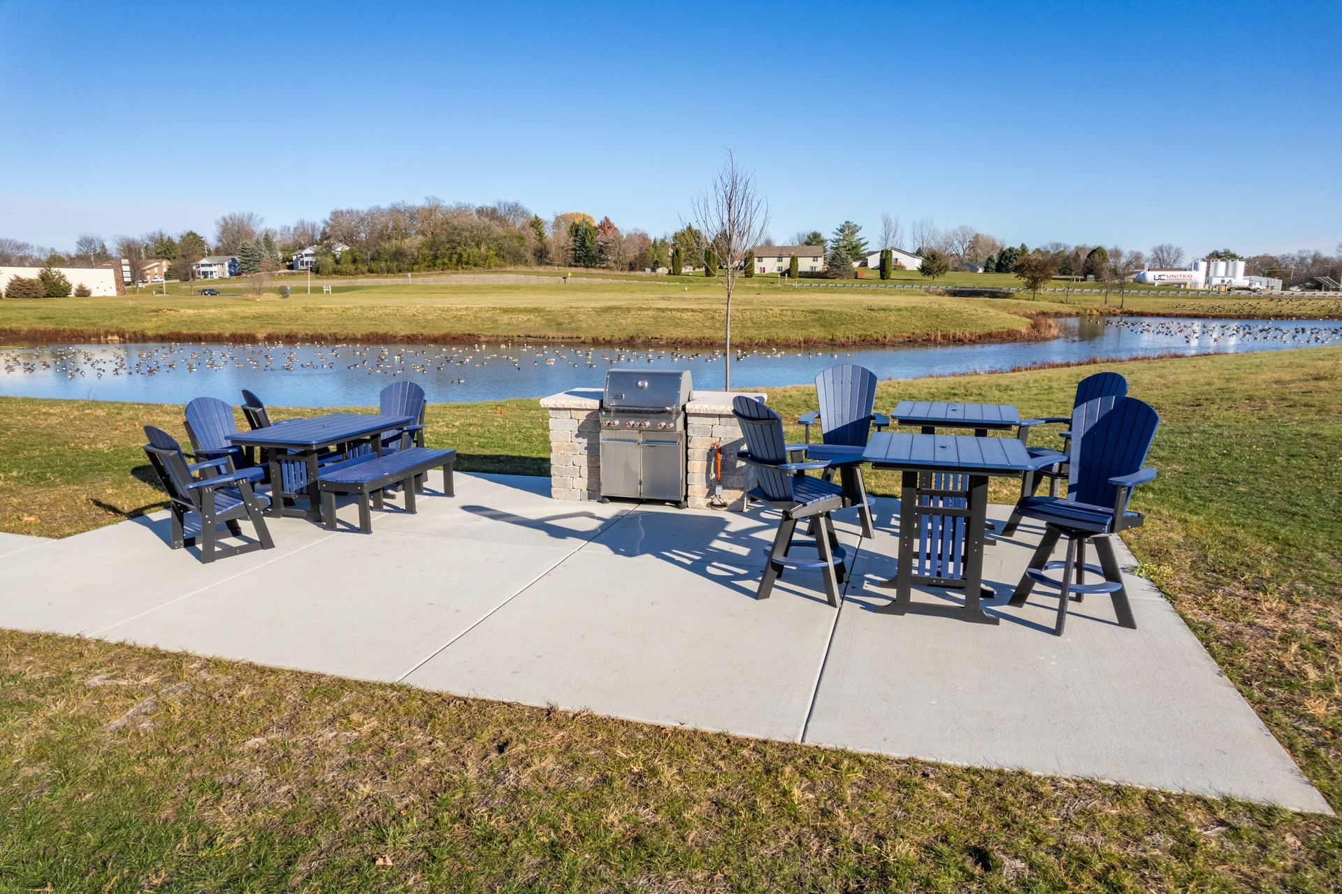 a patio area with tables and chairs and a grill
