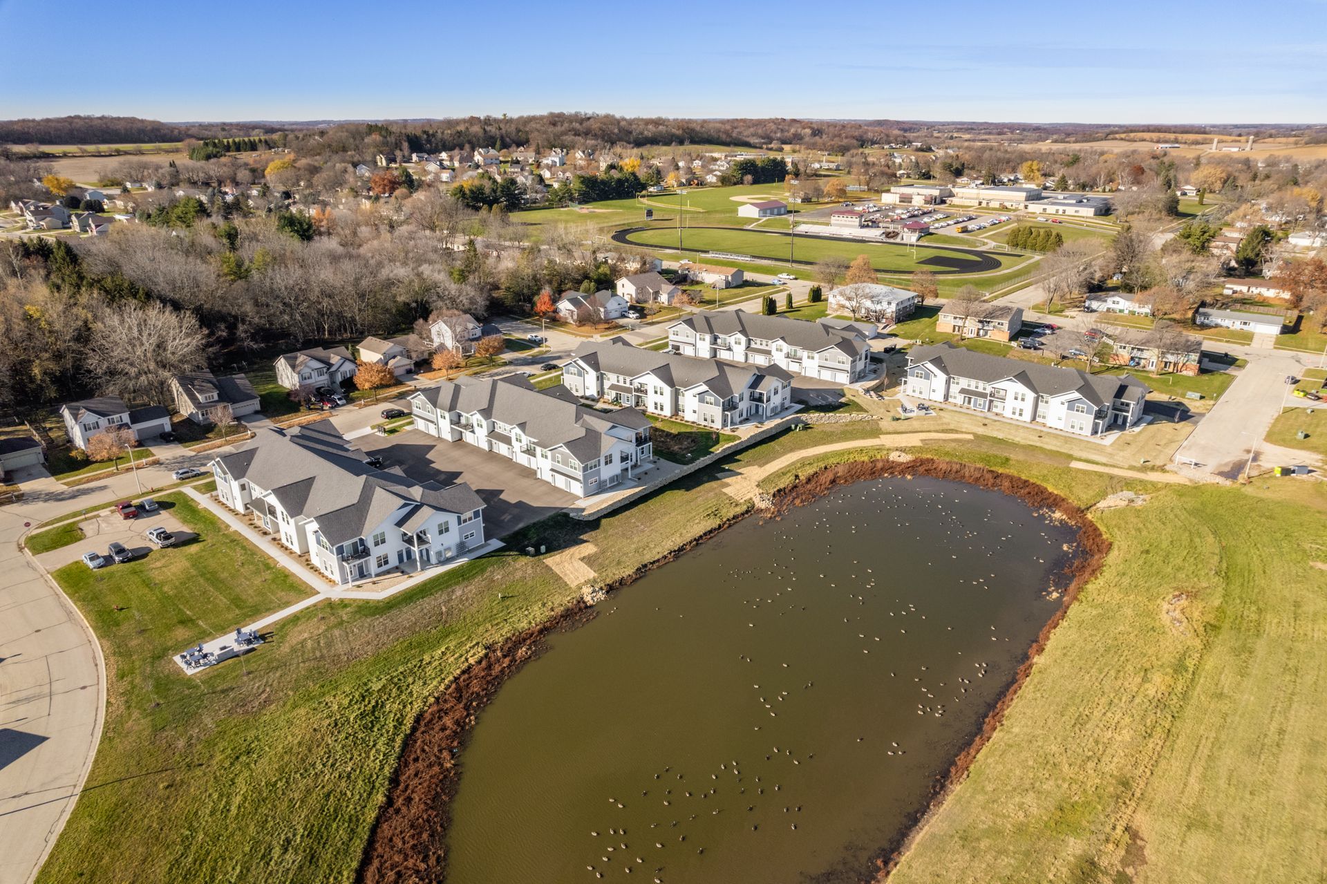 an aerial view of a residential area with a pond in the middle