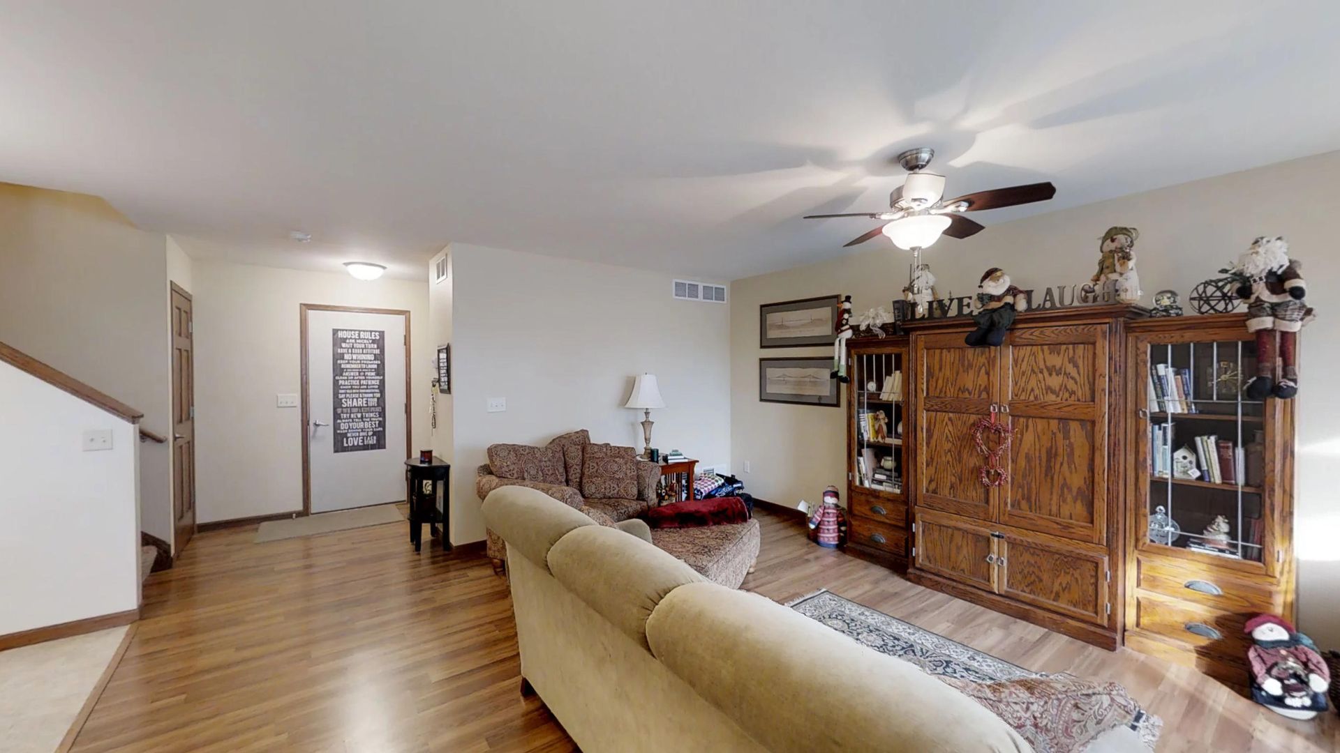 a living room with a ceiling fan and a sign that says laugh