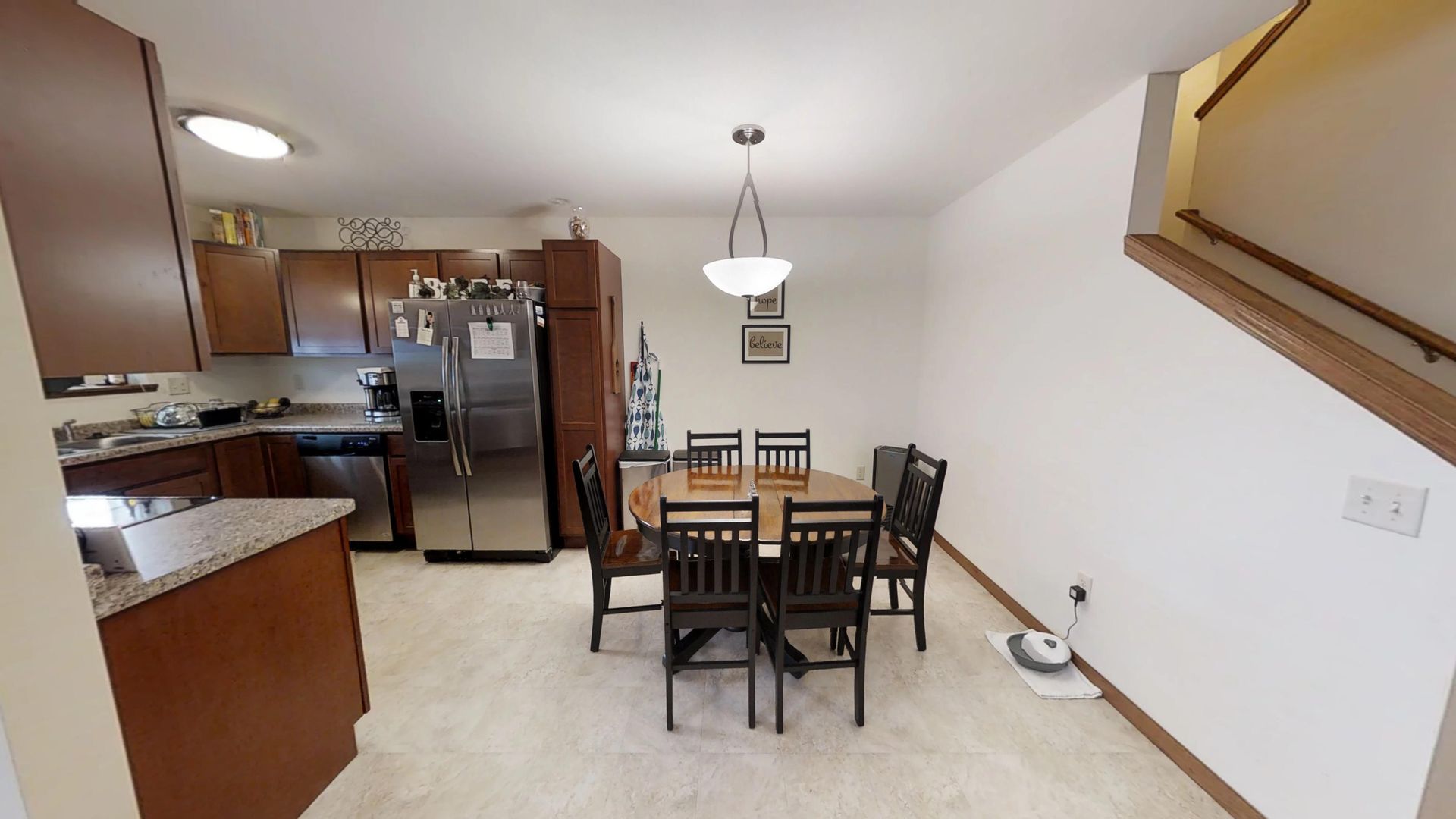 a kitchen with a table and chairs and a stainless steel refrigerator