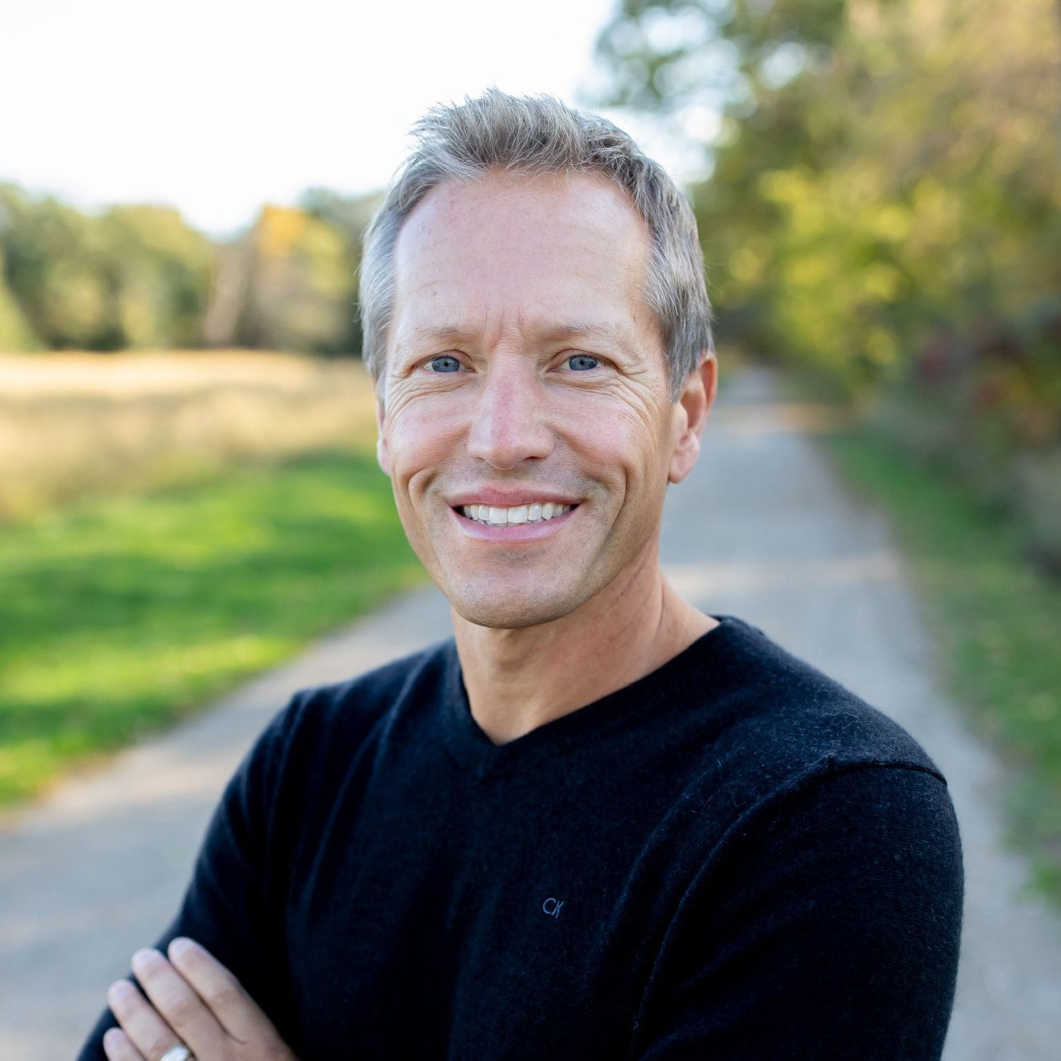 a man wearing a black calvin klein sweater smiles for the camera