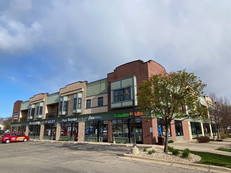 a red car is parked in front of a building with a green sign that says ballastes mills