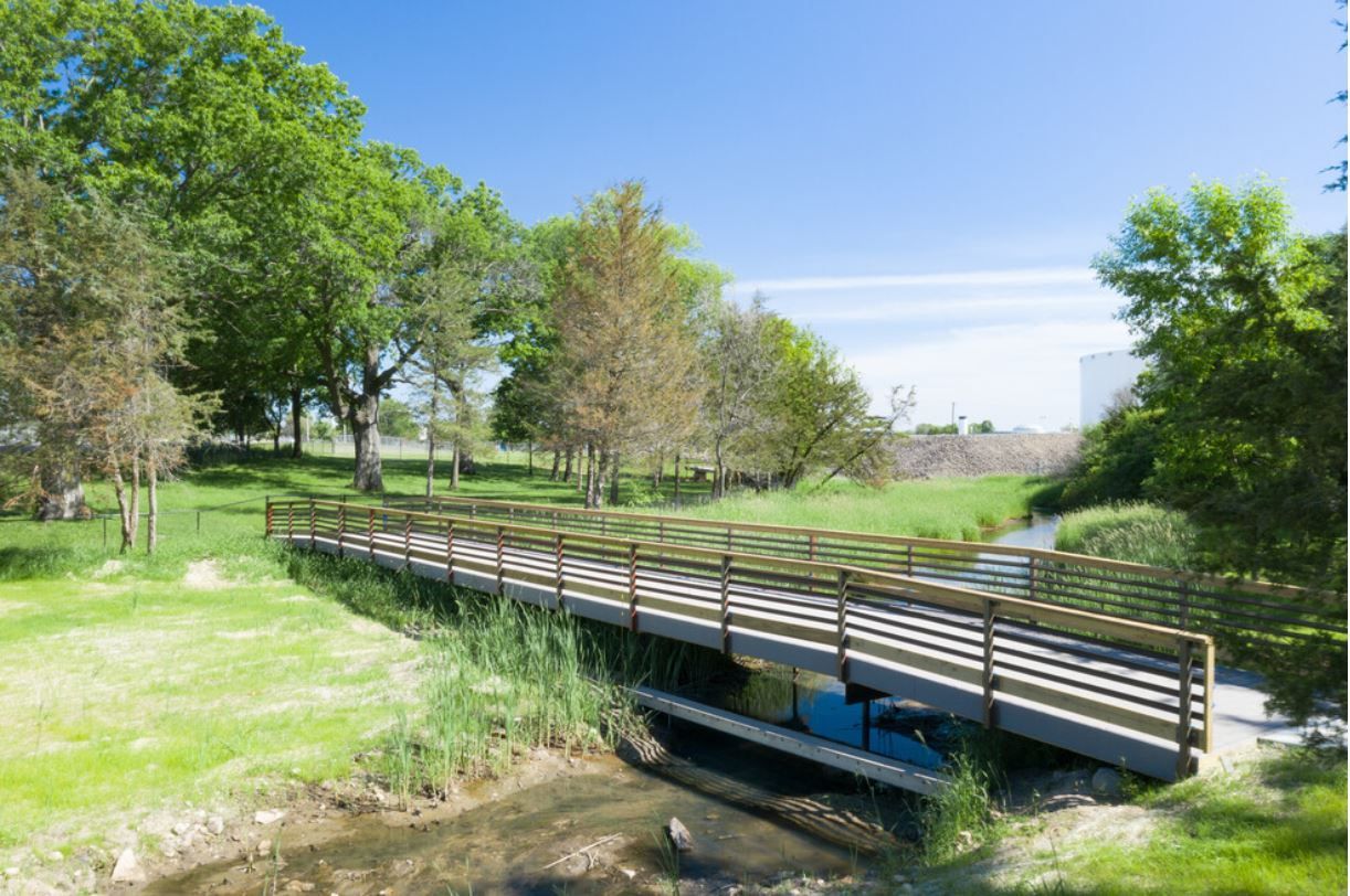 a wooden bridge over a stream in a park