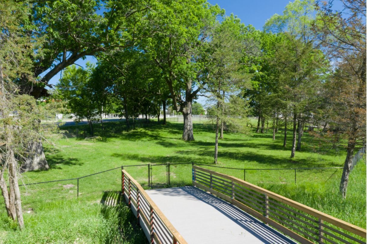 a bridge over a grassy field with trees in the background