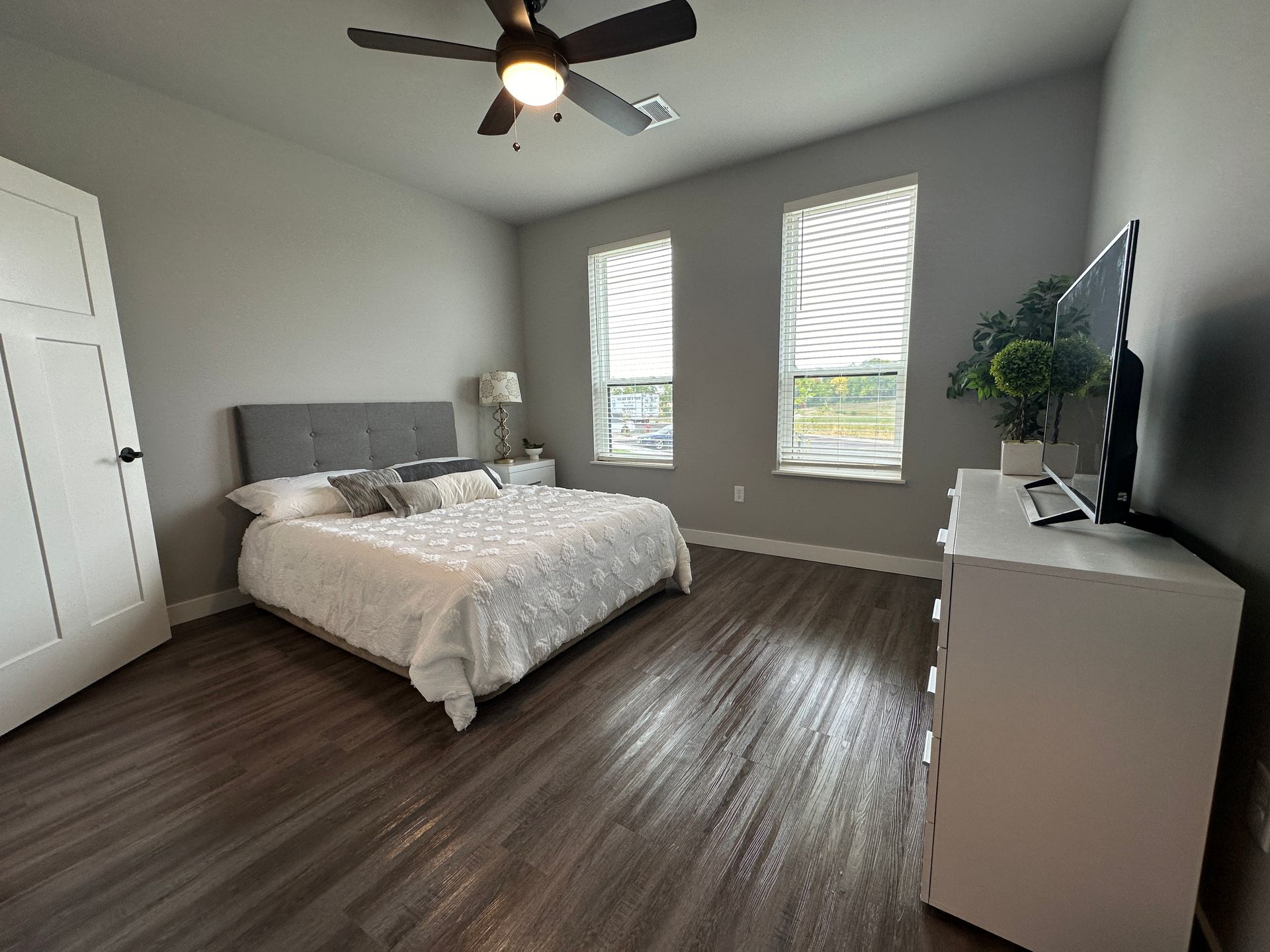 a bedroom with a ceiling fan and a flat screen tv