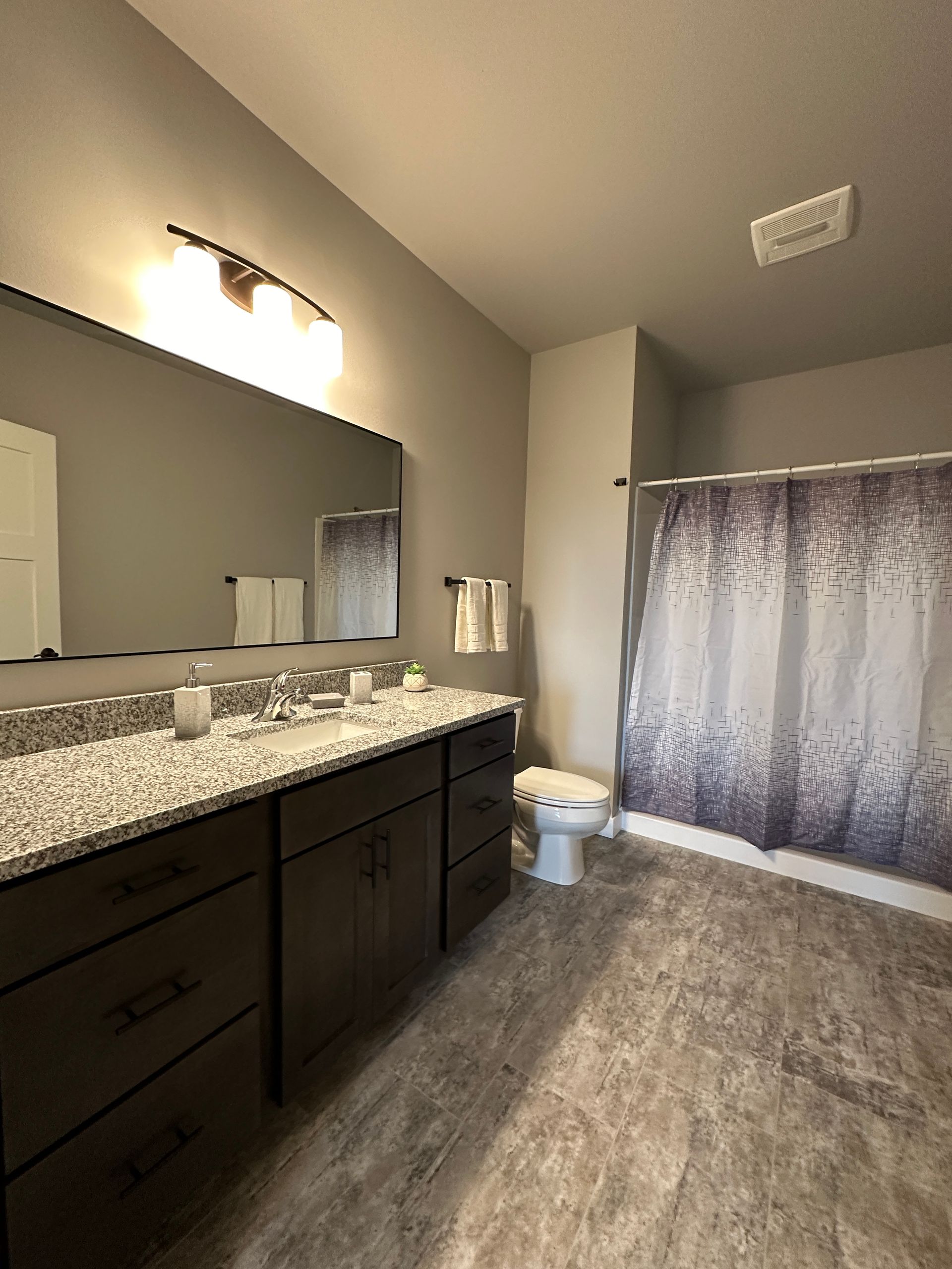 a bathroom with two sinks a toilet and a shower curtain